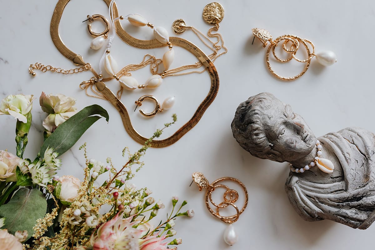 kaboompics Gold jewellery in white marble flowers and a small sculpture a shell